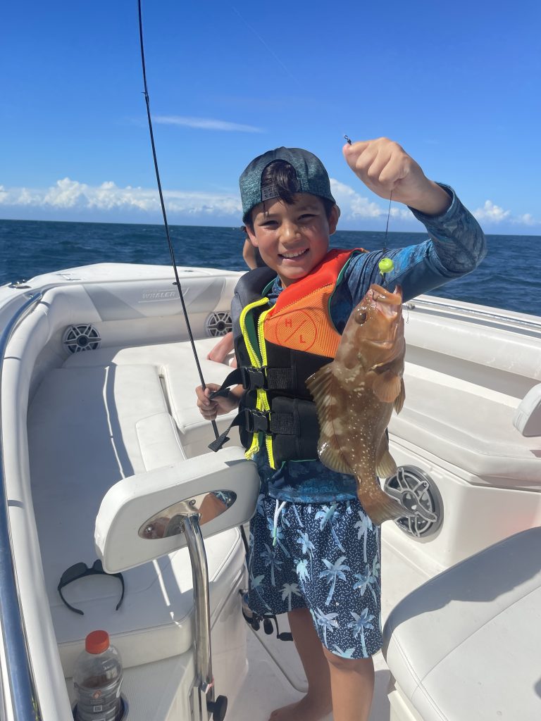 kid holding grouper on fishing line kid holding grouper on fishing line