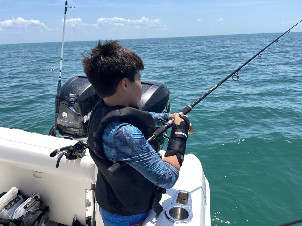 kid fishing off the side of a boat
